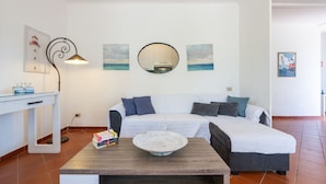 A modern living room with a white sofa, a round mirror, and artwork on the walls. - Villa Angela by Interhome (Pula)