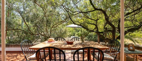 An outdoor dining area with a wooden table and chairs, surrounded by trees.