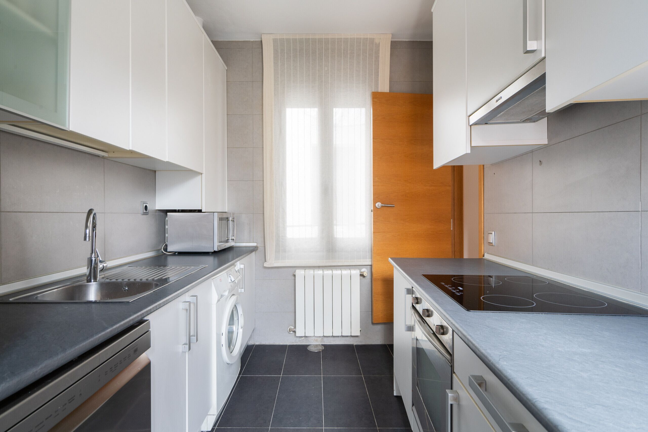 A compact kitchen with a built-in washing machine, a stovetop, and a microwave.