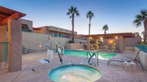 Un área de piscina con sillas de descanso, un jacuzzi y palmeras.