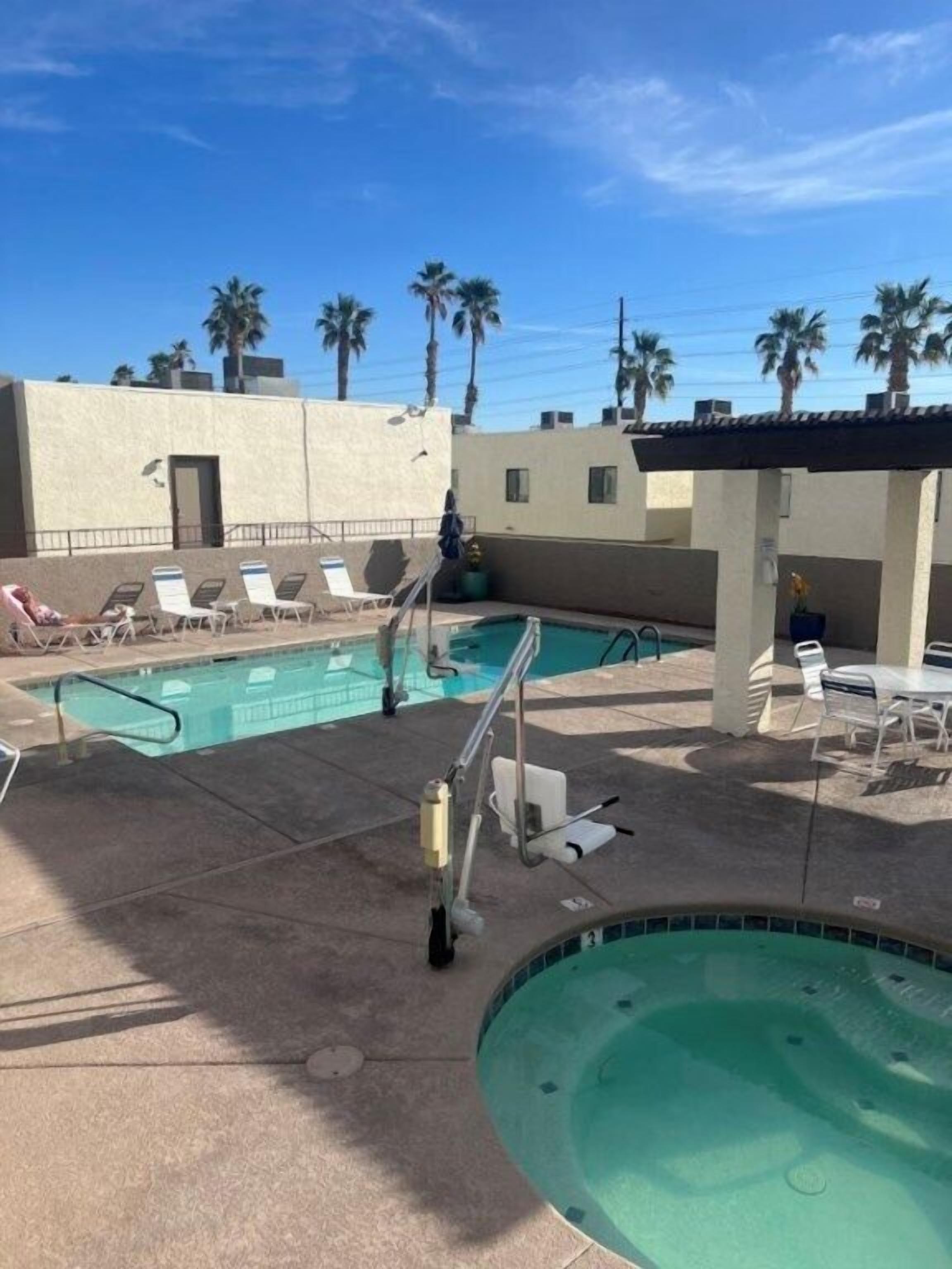 Un área de piscina con sillas de descanso, un trampolín y un pequeño jacuzzi.