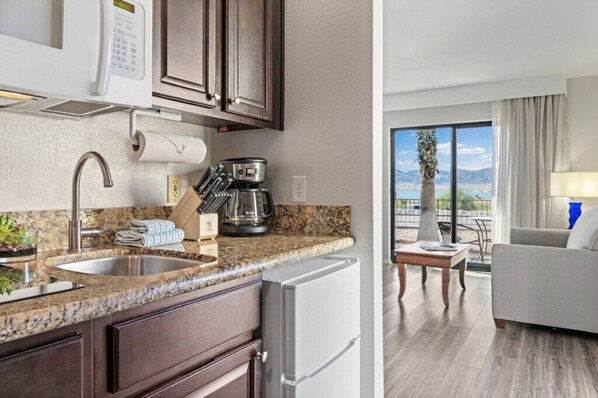 A modern kitchen with granite countertops, a built-in oven, and a coffee maker.