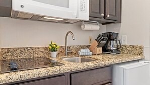 A kitchen with a granite countertop, stainless steel sink, a microwave, a coffee maker, and a knife block. - Lake Havasu City | Couples Lake Retreat | Pool + Hot Tub (Lake Havasu)