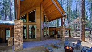 A rustic cabin with a stone fireplace, outdoor seating, and large windows overlooking a forest. - Luxury Cabin in a woods! Private location 7000 ft elevation, 4 seasons! (Prescott)