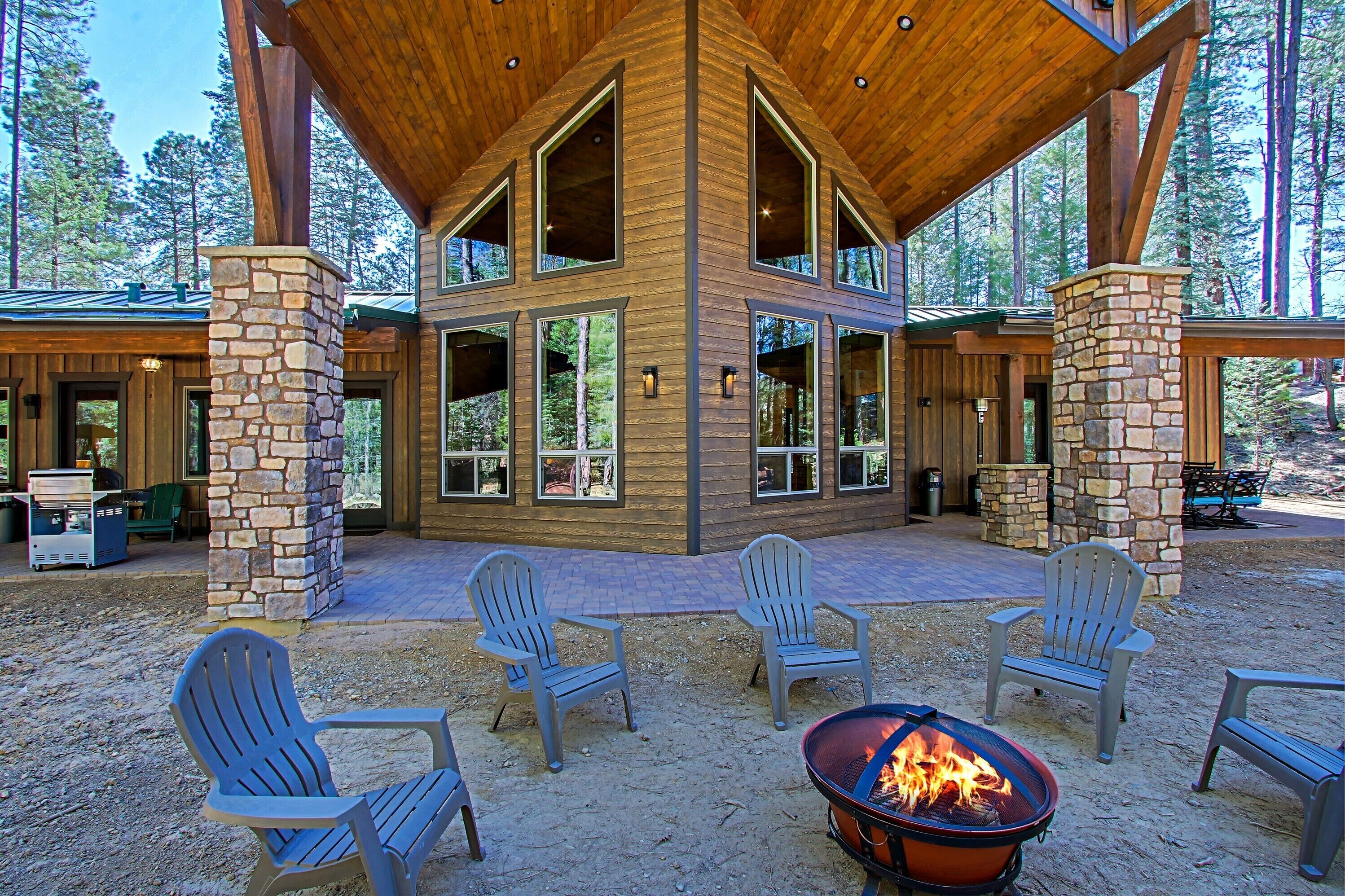 A lodge with a stone fireplace, outdoor seating, and large windows.