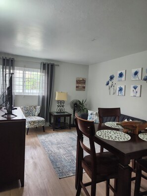 Relax in this stylish living space with a dining area, comfortable sofa, and large window offering a view of the surrounding greenery.
