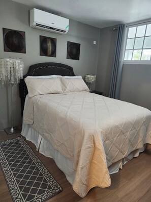 Relax in this serene bedroom with a large bed, air conditioning, and beautiful artwork.