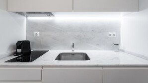 Eine moderne Küche mit Spülbecken aus Edelstahl, einer Kaffeemaschine und einem eingebauten Dunstabzug.