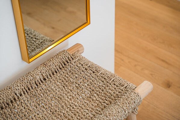 A woven cat toy attached to a wooden post, with a mirror reflecting part of the room.
