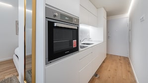 Eine moderne Küche mit weißen Schränken, einem eingebauten Backofen und einer Spüle aus Edelstahl.