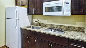 A kitchen with dark wooden cabinets, a white refrigerator, a built-in microwave, a granite countertop, a stainless steel sink, and a gas stove. - Pinetop | Couples Mountain Retreat | Hot Tub + Forest (Pinetop)
