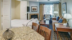 A hotel room with a bed, a sofa, a dining table, and a fireplace. - Pinetop | Couples Mountain Retreat | Hot Tub + Forest (Pinetop)