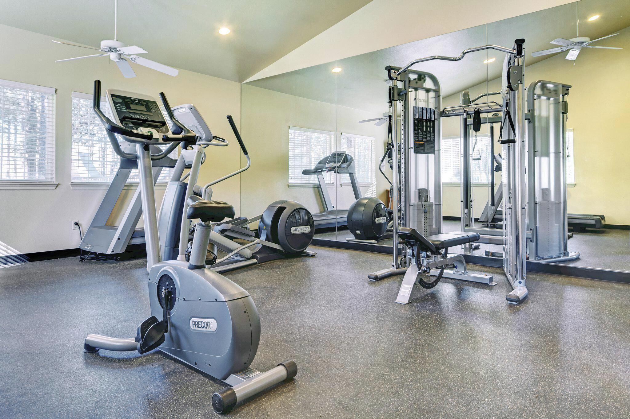 Ein Fitnessstudio mit Cardiogeräten, Gewichten und Spiegeln an den Wänden.