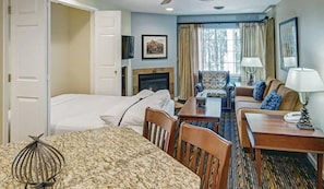 A hotel room with a bed, a sofa, a dining table, and a fireplace. - Pinetop | Couples Forest Hideaway | Hot Tub + Mountains (Pinetop)