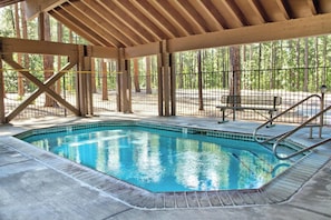 An indoor swimming pool with a wooden deck and metal railing. - Pinetop | Couples Forest Hideaway | Hot Tub + Mountains (Pinetop)