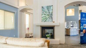 A modern hotel lobby with a fireplace, a seating area, and a reception desk. - Oro Valley | Couples Desert Stay | Pool + Hot Tub (Oro Valley)