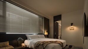 A modern hotel room with a large bed, a bedside table with a lamp, a sofa, and a wall-mounted TV. - WEZO HOTEL CHENGDU (Chengdu)