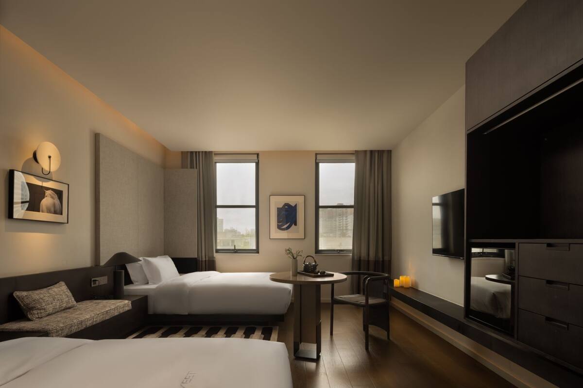 A modern hotel room with a bed, a sofa, a small table, and a TV.