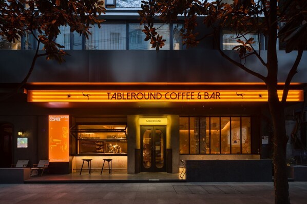 A modern coffee and bar named 'Tableround Coffee & Bar' with a prominent illuminated sign, a seating area outside, and a visible entrance. - WEZO HOTEL CHENGDU (Chengdu)