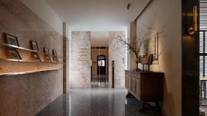A hallway with marble walls, a polished floor, and a wooden cabinet with a vase. - WEZO HOTEL CHENGDU (Chengdu)