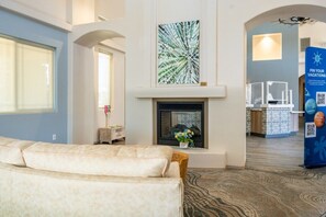 A modern hotel lobby with a fireplace, a seating area, and a reception desk. - Oro Valley | Couples Desert Escape | Pool + Hot Tub (Oro Valley)