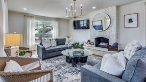 A living room with a sofa, a coffee table, a fireplace, and a large mirror. - Stunning Lake House with a Pool and Hot Tub (Lakewood Village)