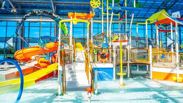 An indoor water park with slides, splash pads, and play structures. - Stunning Lake House with a Pool and Hot Tub (Lakewood Village)