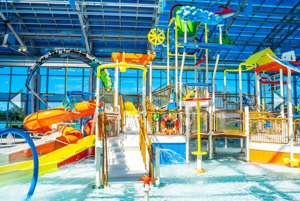 An indoor water park with slides, splash pads, and play structures.