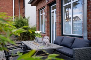 Une terrasse avec une table, des chaises et un canapé.