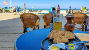 Een tafel met een fles Blanche de Narmer, een glas geel drankje, sneetjes brood, boter en een zoutvaatje.