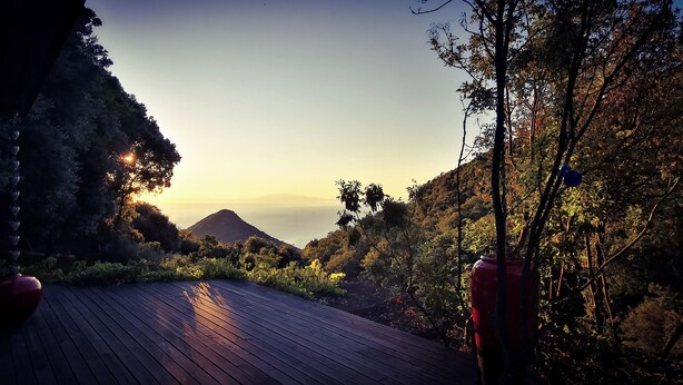 A wooden deck leading to a mountainous landscape with a clear sky.
