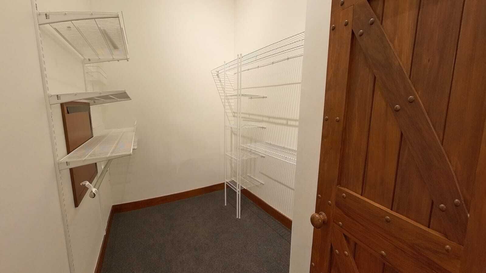 A small, narrow room with white shelving units and a wooden door.