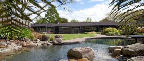 A modern building with a swimming pool, surrounded by rocks and greenery.