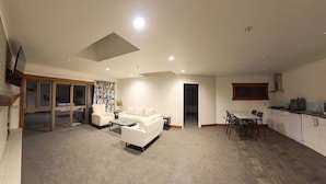 Una sala moderna con un sofá, una mesa de centro y un comedor con mesa y sillas. Hay una zona de cocina con armarios y una ventana.