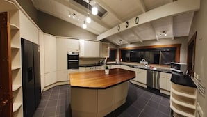 Una cocina moderna con una isla central, electrodomésticos integrados y un ventanal grande.