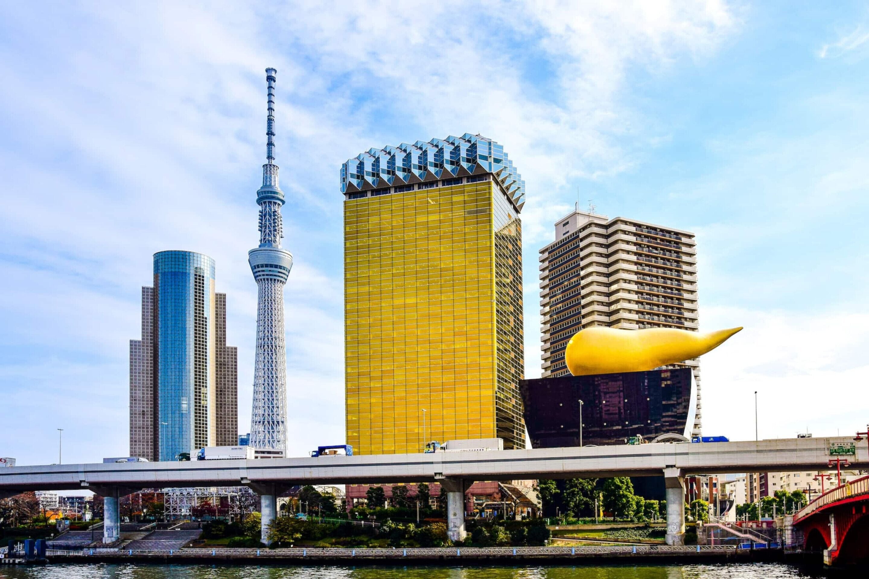 A cityscape with modern skyscrapers, a prominent tower, and a bridge over a body of water.