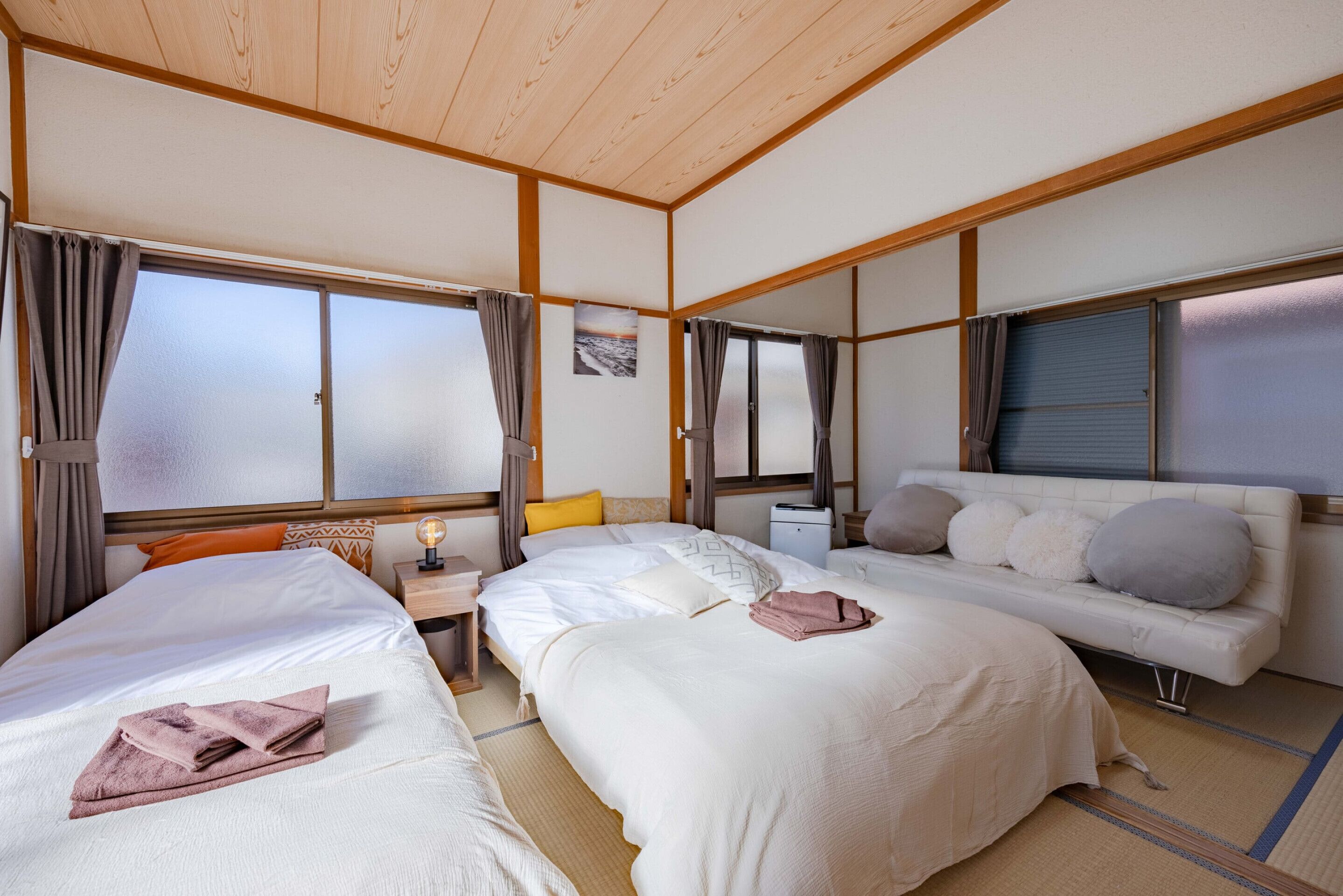 Habitación de hotel con dos camas, un sofá, una mesita de noche y una ventana con cortinas.