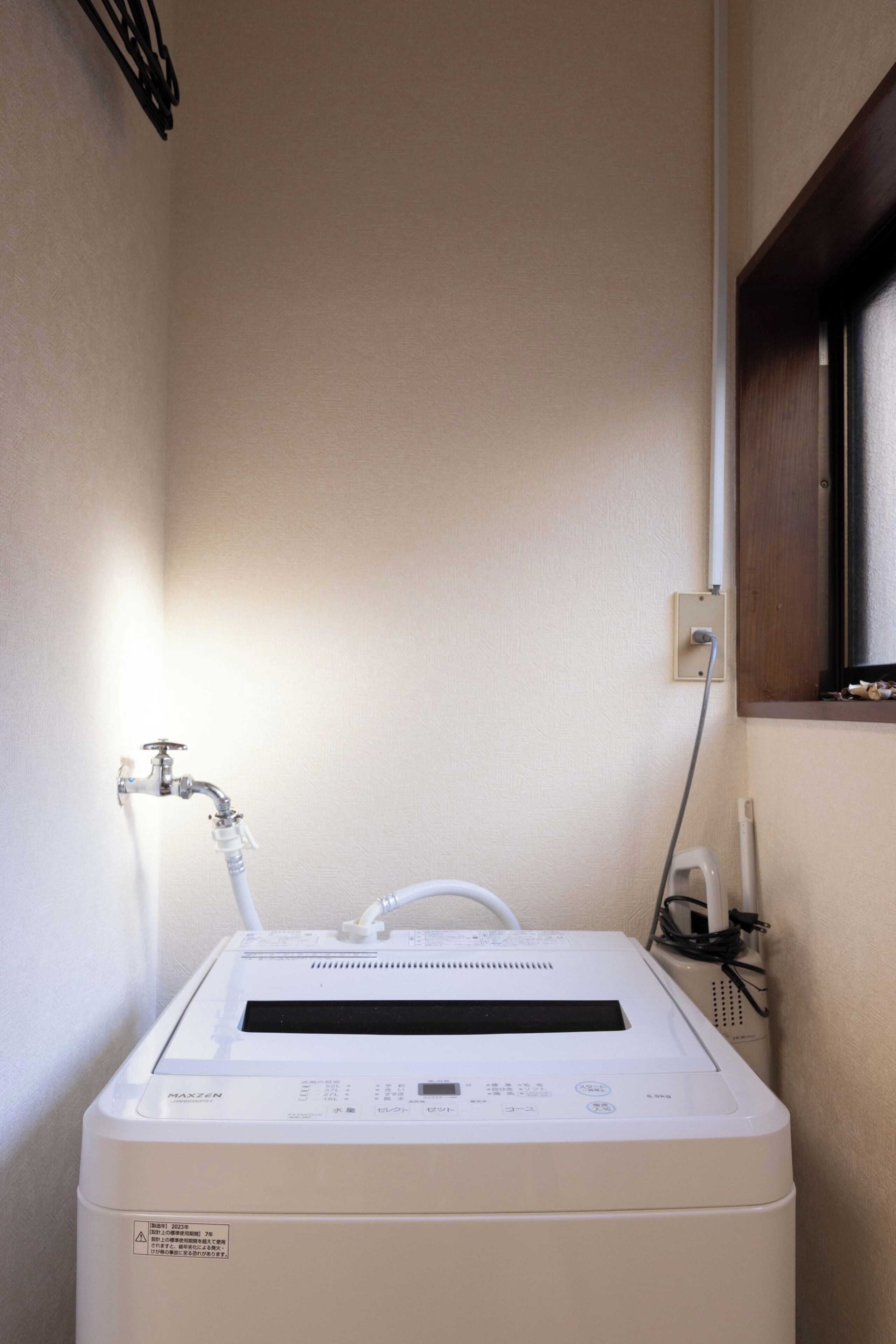 Un chauffe-eau compact de couleur blanche, doté d’un panneau de commande et raccordé à un robinet fixé au mur.
