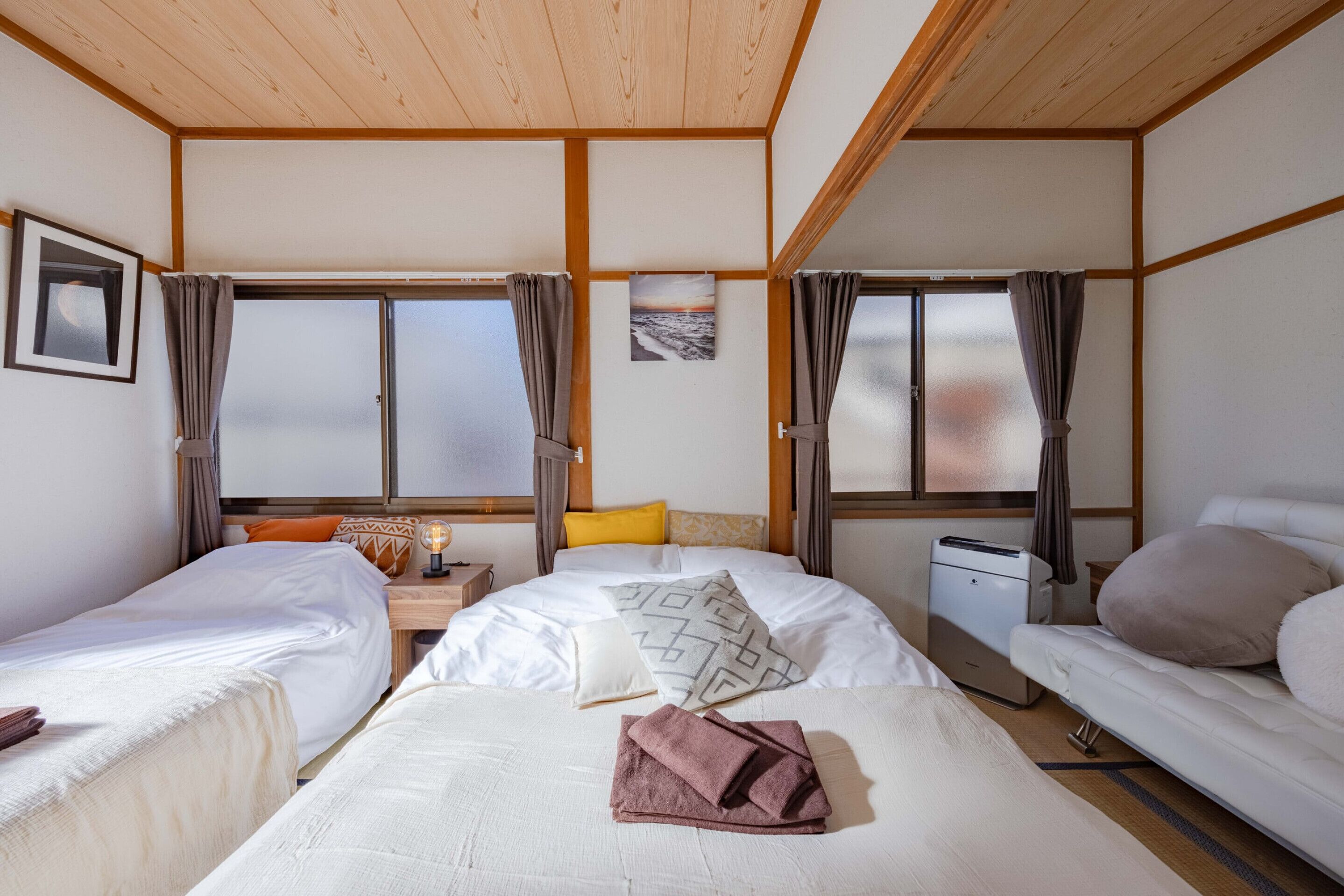 Quarto de hotel com duas camas, uma escrivaninha, impressora e janelas amplas com cortinas.