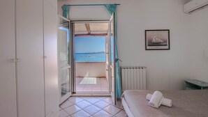 Une chambre avec vue sur la mer, un lit, un radiateur et un tableau encadré au mur.