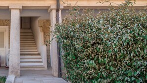Una escalera de piedra que conduce a una puerta, un seto y la fachada de un edificio.
