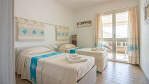 Habitación de hotel con dos camas, un balcón y vistas del paisaje.