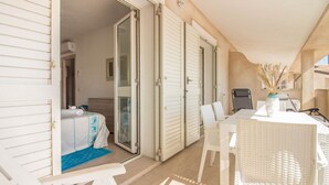 Una habitación con cama, una mesa con sillas y una puerta corredera que da a otra estancia.