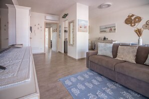 A modern living room with a sofa, a blue patterned rug, and a kitchen area in the background.