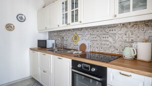 Una cocina con armarios blancos, un microondas, una estufa y un salpicadero con diseño.
