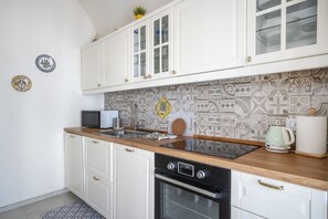 Una cocina con armarios blancos, un microondas, una estufa y un salpicadero con diseño.