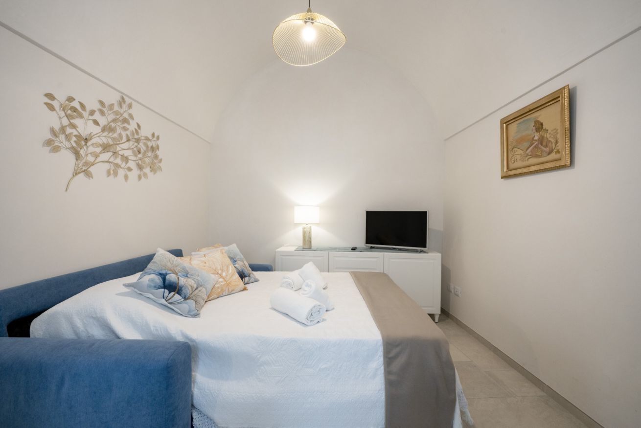 Quarto com uma cama, televisão, abajur e um quadro na parede.