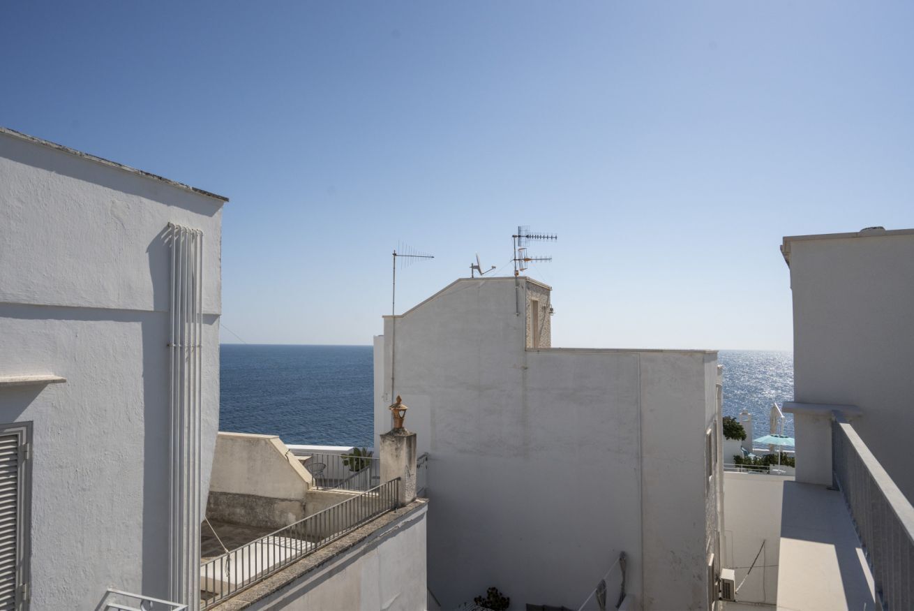 A coastal building with a balcony overlooking the sea, featuring a simple architectural design and a clear view of the ocean.