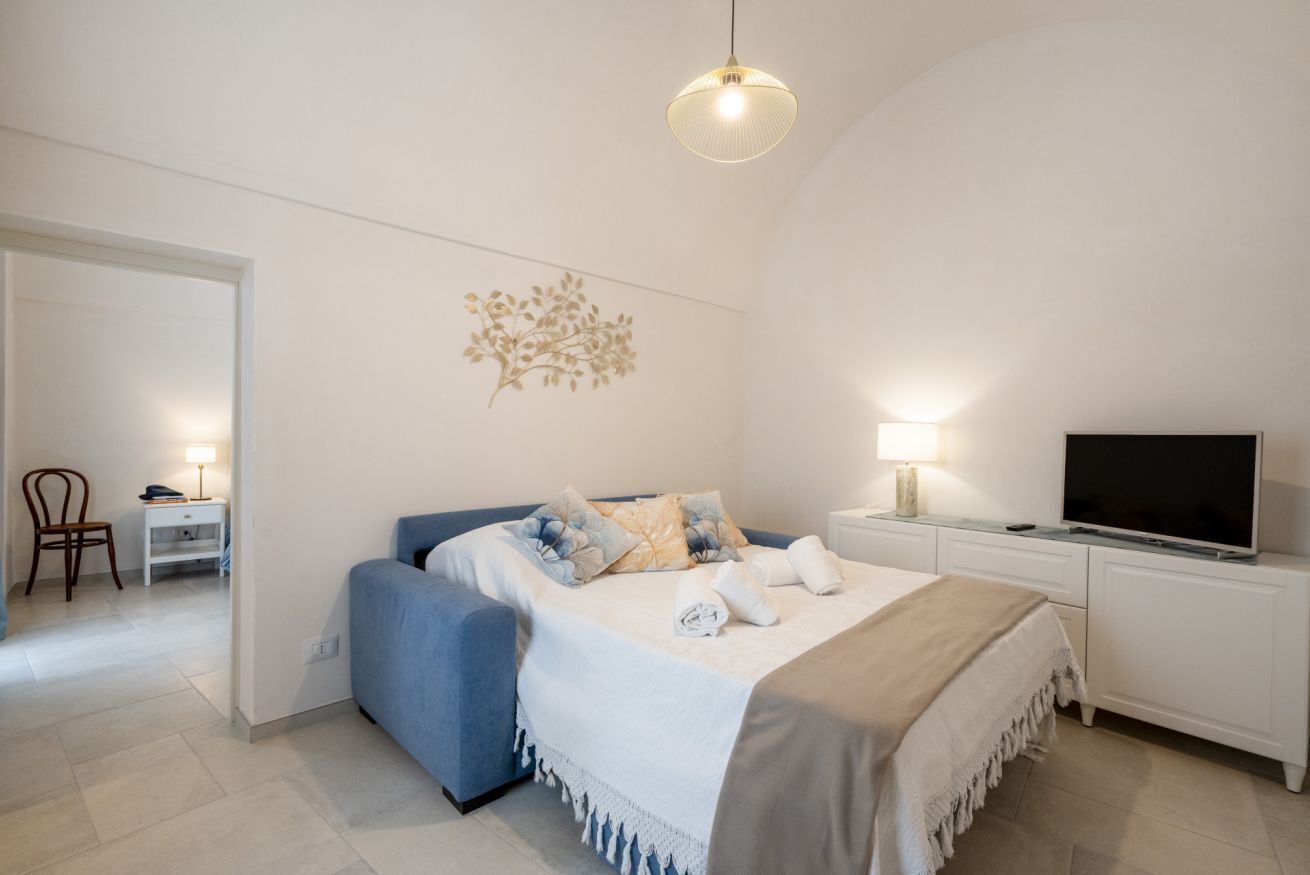 A bedroom with a bed, bedside table, TV, and a wall decoration.