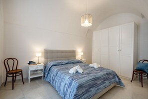 Une chambre à coucher comprenant un lit, deux tables de chevet avec des lampes, une armoire et deux chaises.